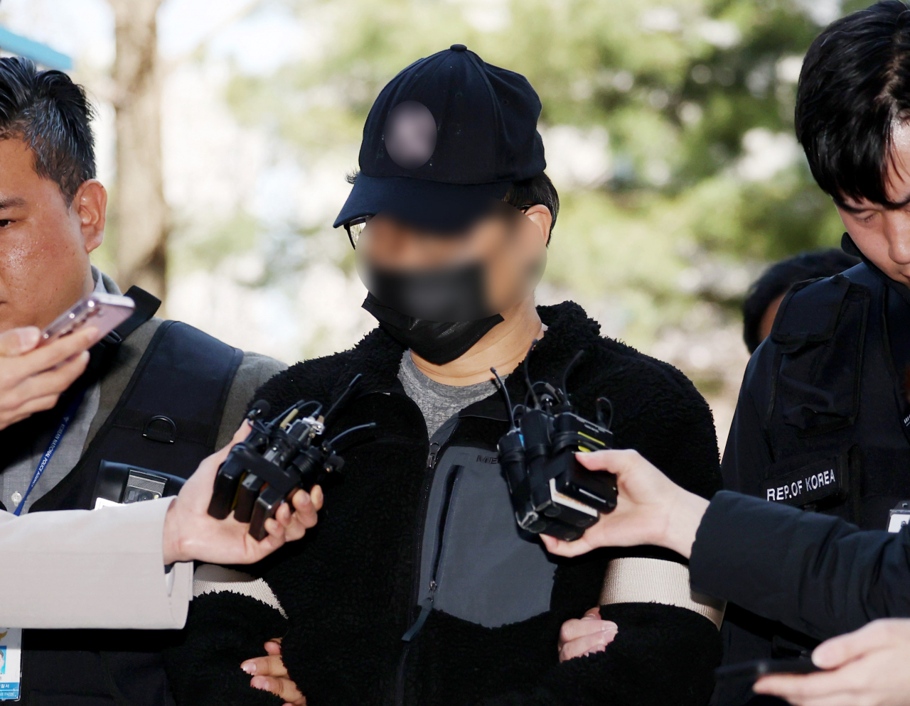 The suspect accused of installing illegal cameras at 41 polling stations nationwide is escorted by the police to attend a review of his arrest warrant at Incheon District Court on Sunday. (Yonhap)