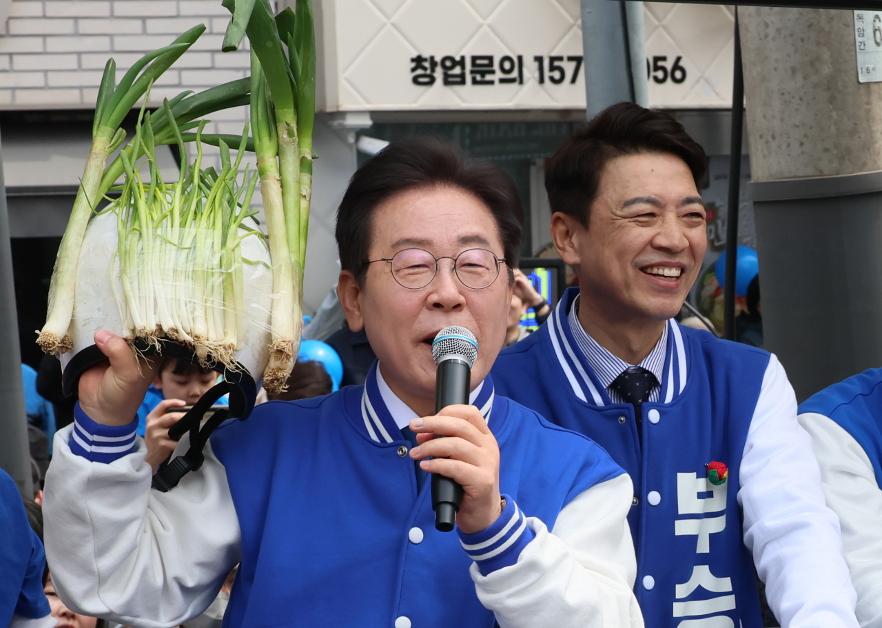 Main opposition leader Rep. Lee Jae-myung (left) holds a helmet with scallions attached during his visit to Yongin, Gyeonggi Province on Saturday. (Yonhap)