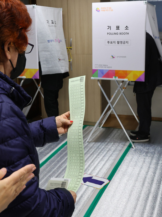 A voter looks at a ballot for the 22nd general election, the longest ballot in history, with 38 parties registered to compete for proportional representation seats in the National Assembly, at a polling station in Namdong-gu, Incheon, Wednesday. (Yonhap)