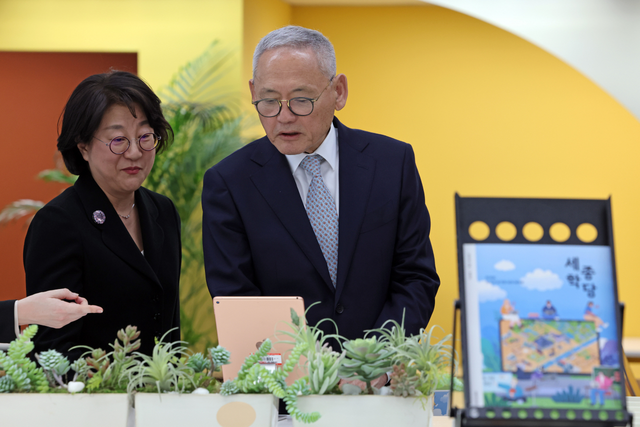 Culture Minister Yu In-chon (right) and Lee Hai-young, president of the King Sejong Institute Foundation, view education materials of the King Sejong Institute at the foundation headquarters in Gangnam-gu, Seoul, Friday. (Culture Ministry)