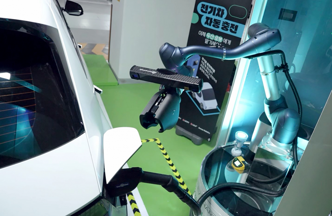 A robotic arm, part of the collaborative charging system co-developed by Doosan Robotics and LG Electronics, retracts a charging cable from the port of an Ioniq 5 electric vehicle upon charging completion. (Doosan Robotics)