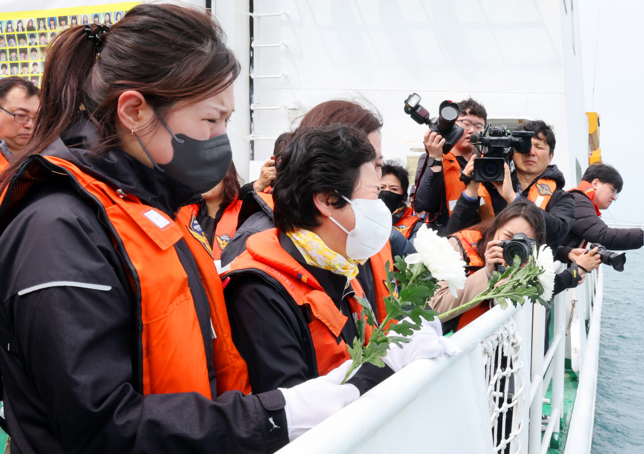 A bereaved family member tosses a flower during a memorial service held near Donggeochado of Jindo County, South Jeolla Province, Tuesday, in memory of victims who died 10 years prior on a ferry that sank on its way to Jeju Island on April 16, 2014. (Yonhap)