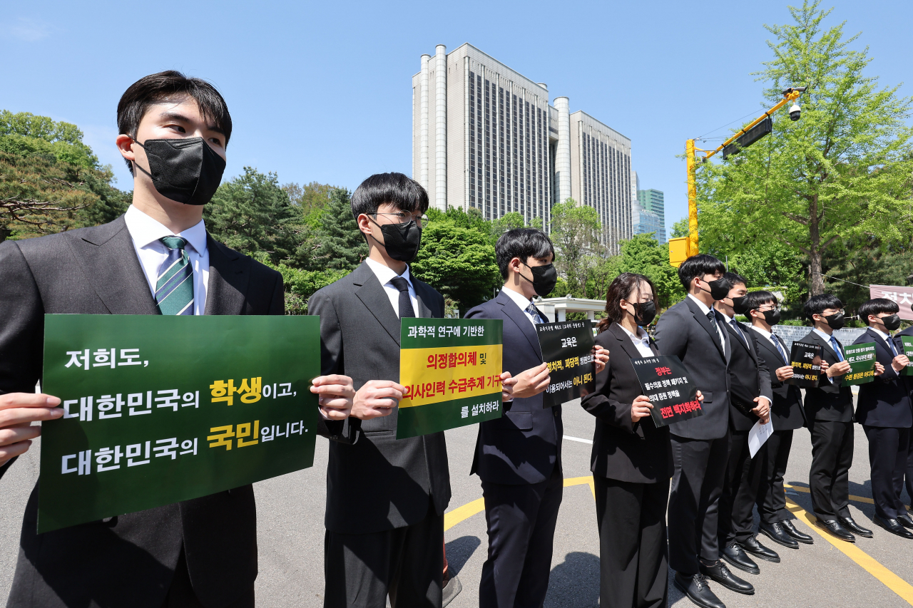 Medical students hold placards opposing the government’s expansion plan in front of the Seoul Central District Court on Monday. (Yonhap)