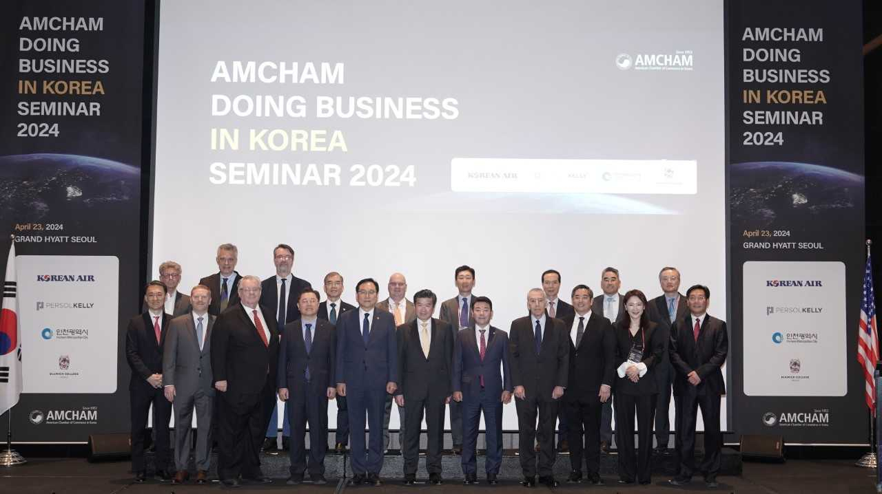 Korea’s Trade Minister Cheong In-kyo (fifth from left), American Chamber of Commerce CEO James Kim (sixth from left) and US Ambassador to South Korea Philip Goldberg (fourth from right) along with other government and business representatives pose for a picture at the Doing Business in Korea Seminar 2024 at the Grand Hyatt Seoul, Tuesday. (AmCham)
