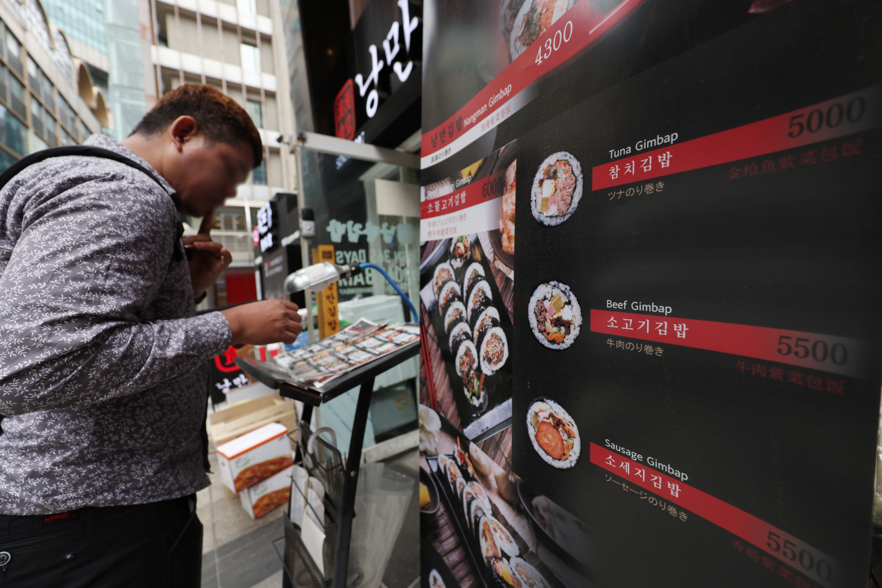A person looks at the menu of a restaurant in Myung-dong, central Seoul on April 3. (Yonhap)
