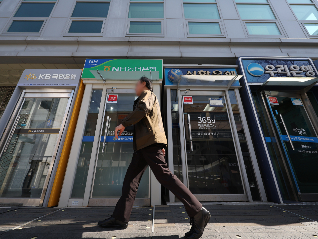 A man walks by ATMs of local banks installed on a street in Seoul on April 9. (Yonhap)