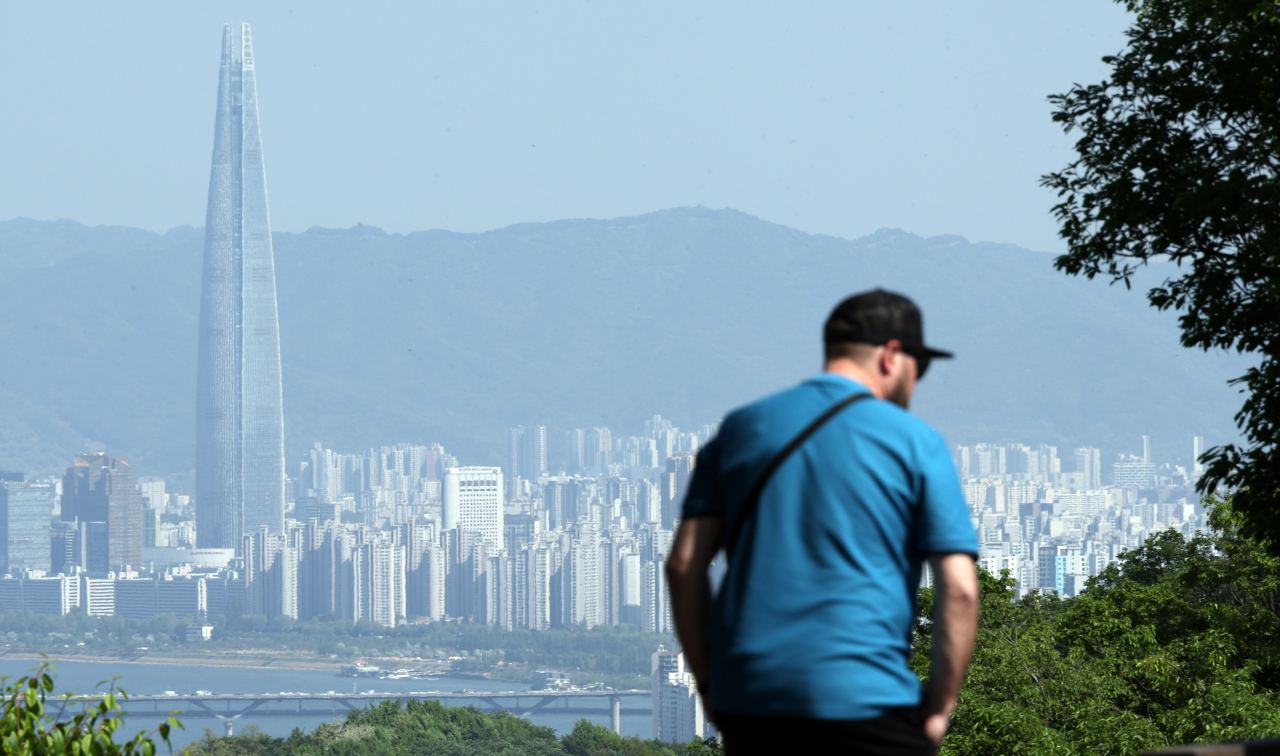 A person stands in front of a view of Seoul's Han River skyline, including the Lotte World Tower. (Yonhap)