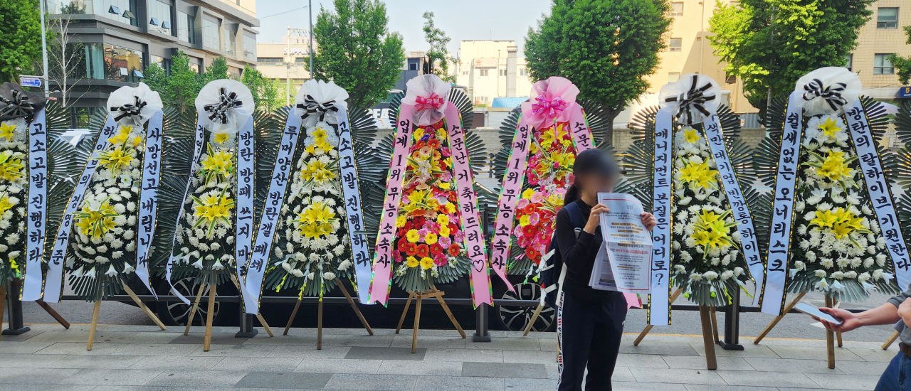 Wreaths of flowers with BTS fans' protesting messages against Hybe and BigHit Music are displayed in front of Hybe's headquarters in Yongsan-gu, Seoul, Friday. (Yonhap)