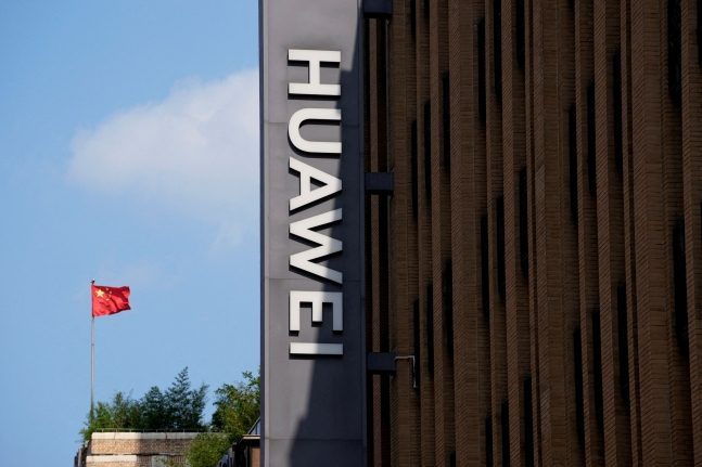 Chinese flag stands next to a Huawei store in Shanghai, China. (Reuters-Yonhap)