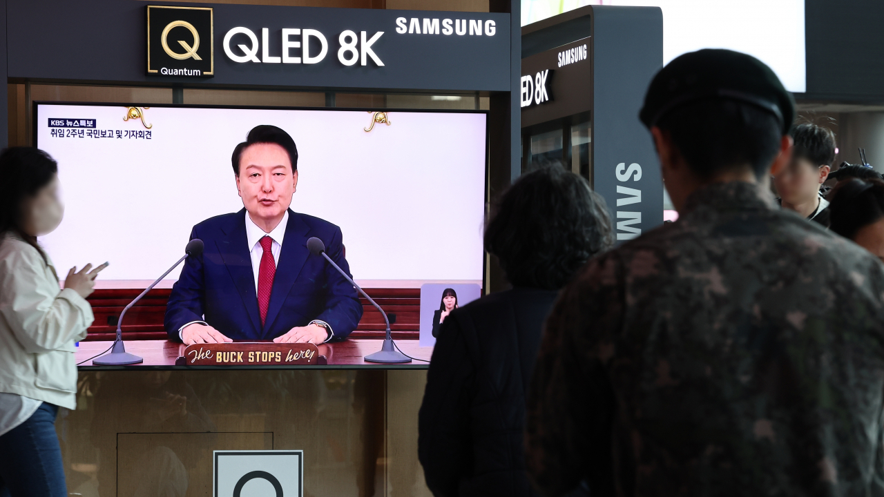 People watch President Yoon Suk Yeol's address to the nation marking the second anniversary of his presidency at Seoul Station in Seoul on Thursday. (Yonhap)