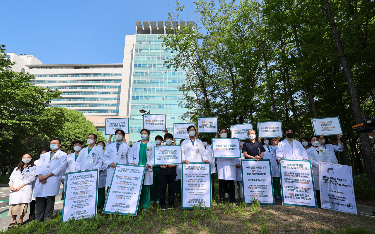 Doctors on a one-day break hold up signs at Asan Medical Center in Seoul on May 3, 2024, calling for the government to abandon its plan to increase medical student enrollment. (Yonhap)