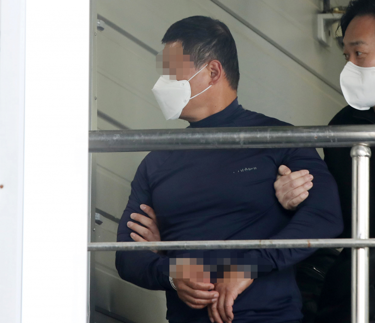 A YouTuber in his 50s is escorted by a police officer in Busan on Thursday after he stabbed to death another YouTuber in front of the Busan District Court. (Joint Press Corp.)