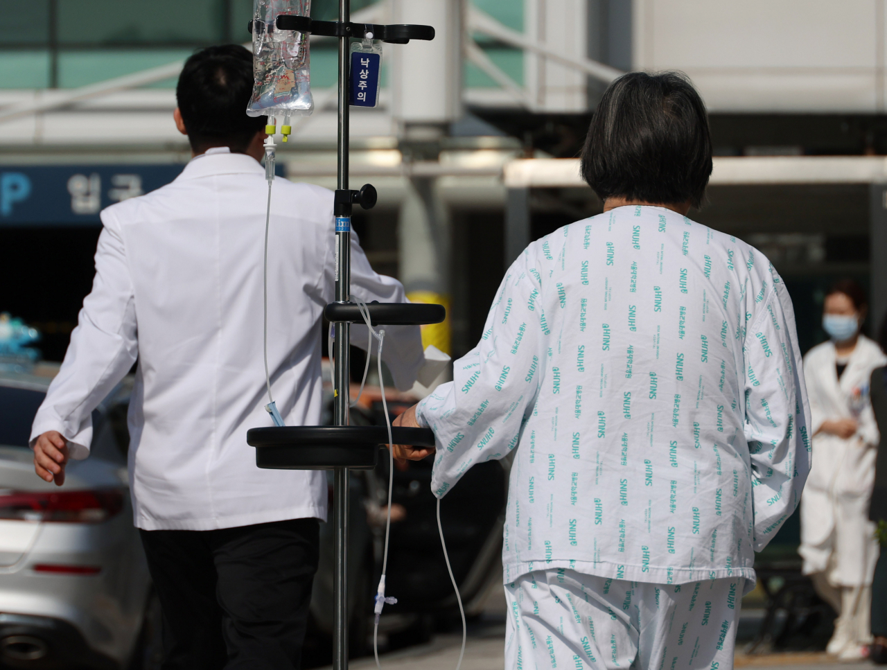 A medical staff and a patient walk outside a hospital in Seoul (Yonhap)