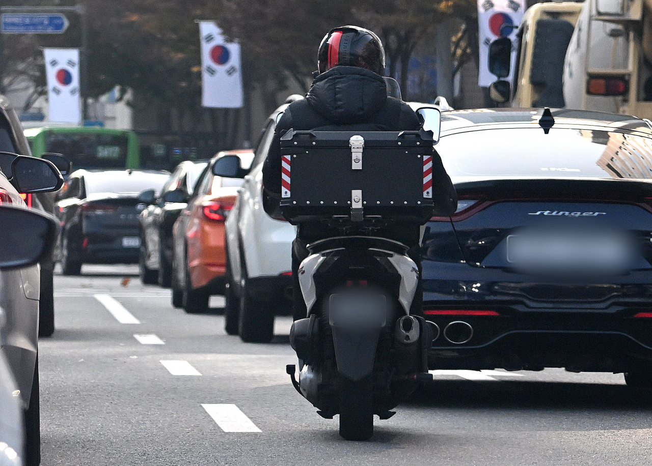 A delivery driver cruises along a street in Seoul. (Im Se-jun/The Korea Herald)