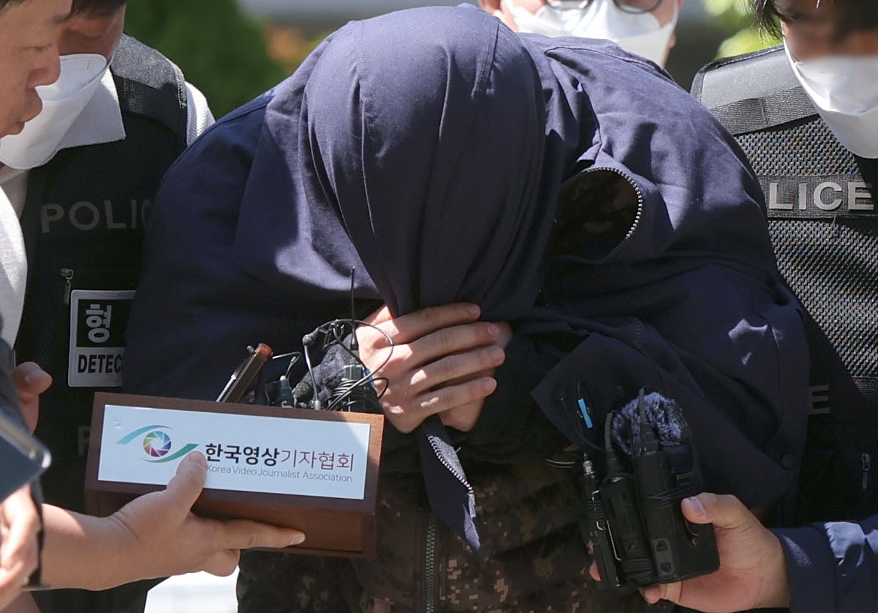 A suspect in the murder of a Korean national in Thailand covers his face with clothes as he is escorted by Korean police for an interrogation Wednesday, in Changwon, South Gyeongsang Province, where he was caught. In Thai media, his name and face have been publicly disclosed. (Yonhap)