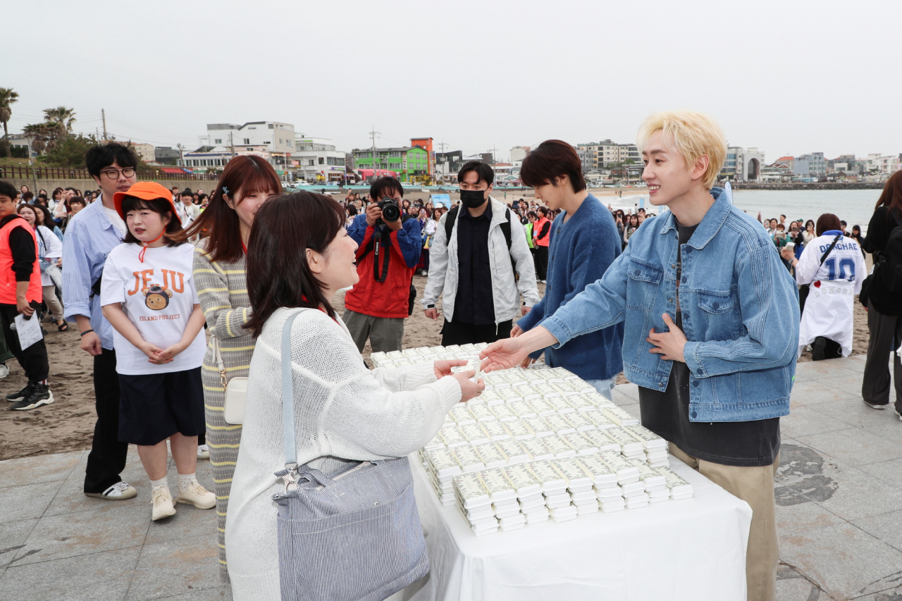 Super Junior-D&E members Eunhyuk (right) and Donghae present gifts to their Japanese fans after a plogging session on Iho Tewoo Beach, northern Jeju Island. (KTO)
