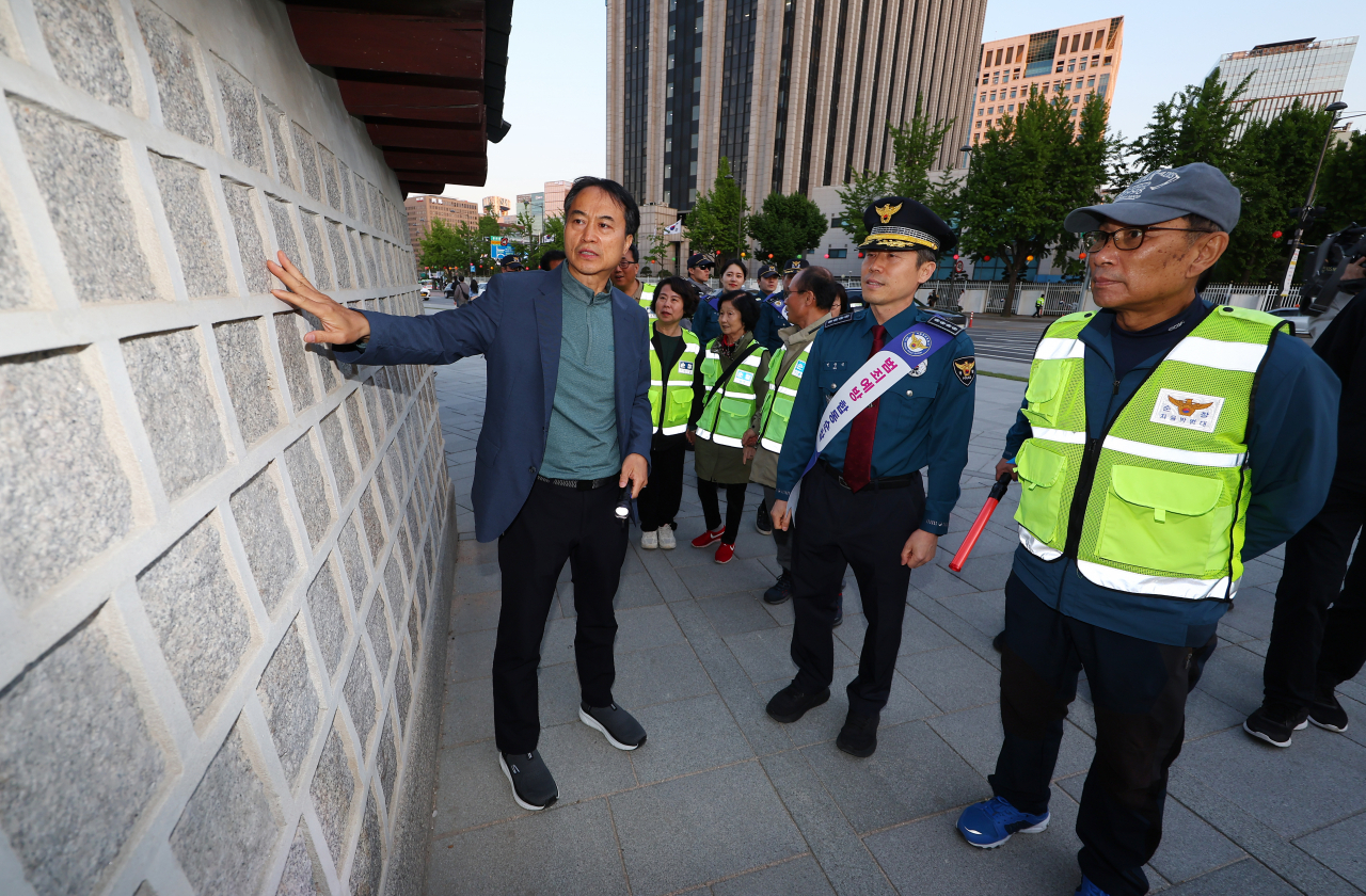 Following the inauguration ceremony of the patrol unit for Gyeongbokgung Palace's outer walls at Gwanghwamun Square in Seoul, Ko Jeong-ju, Director of the Gyeongbokgung Palace Management Office, explains the graffiti vandalism site to attendees on May 8. (Yonhap)