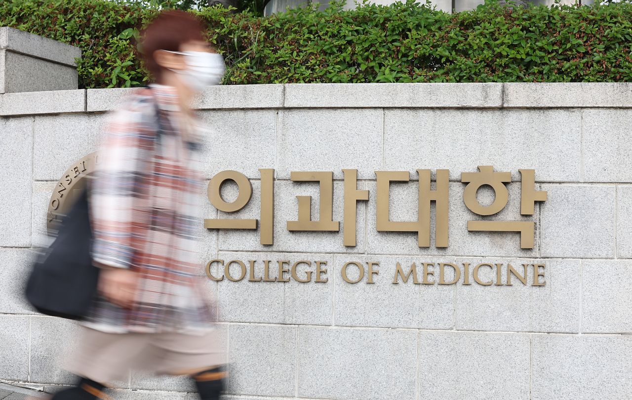 A citizen passes by a medical college in Seoul, on Friday while the Korean Council for University Education held a university admissions committee meeting. (Yonhap)