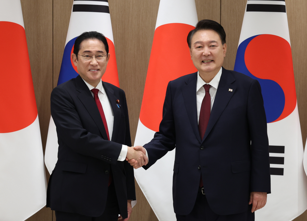President Yoon Suk Yeol (right) shakes hands with Japanese Prime Minister Fumio Kishida during their meeting at the presidential office in Seoul on Sunday. (Yonhap)