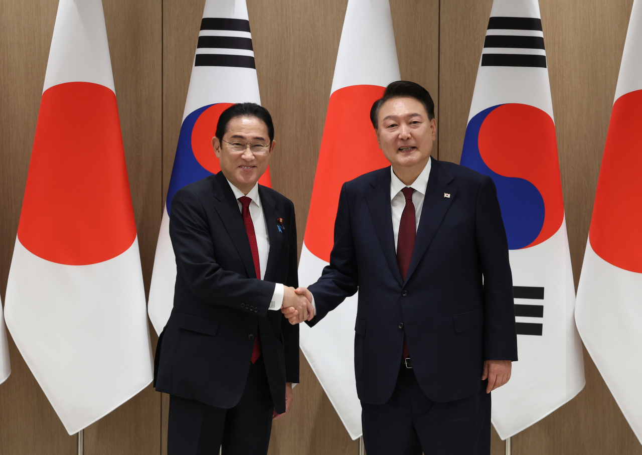 President Yoon Suk Yeol, right, shakes hands with Japanese Prime Minister Fumio Kishida during their meeting at the presidential office in Seoul on Sunday. (Yonhap)