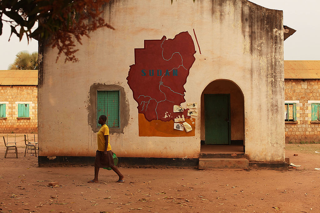 A woman walks by a building with a map of Sudan painted on it. (Getty Images)