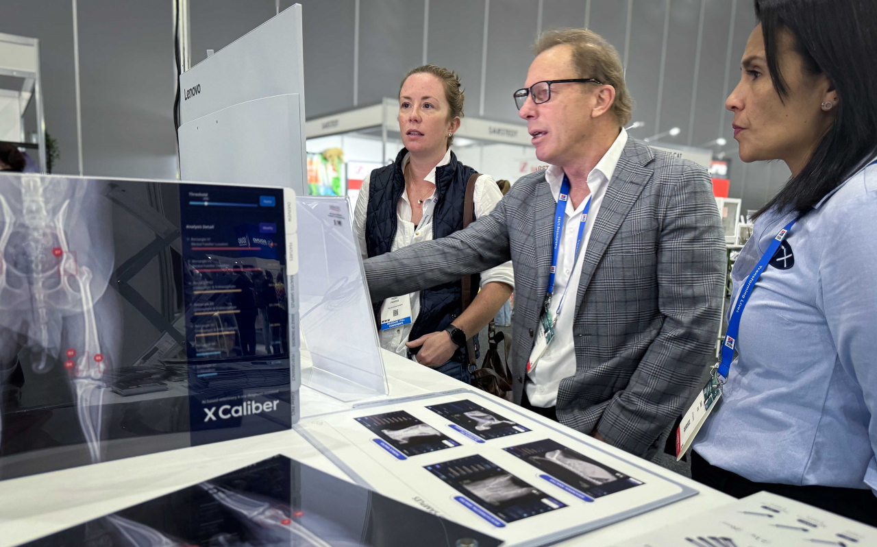 ATX Medical Solutions CEO Roger Davis (center) introduces SK Telecom's X Caliber technology to a veterinarian at the Australian Veterinary Association conference held in Melbourne, Australia, Tuesday. (SK Telecom)