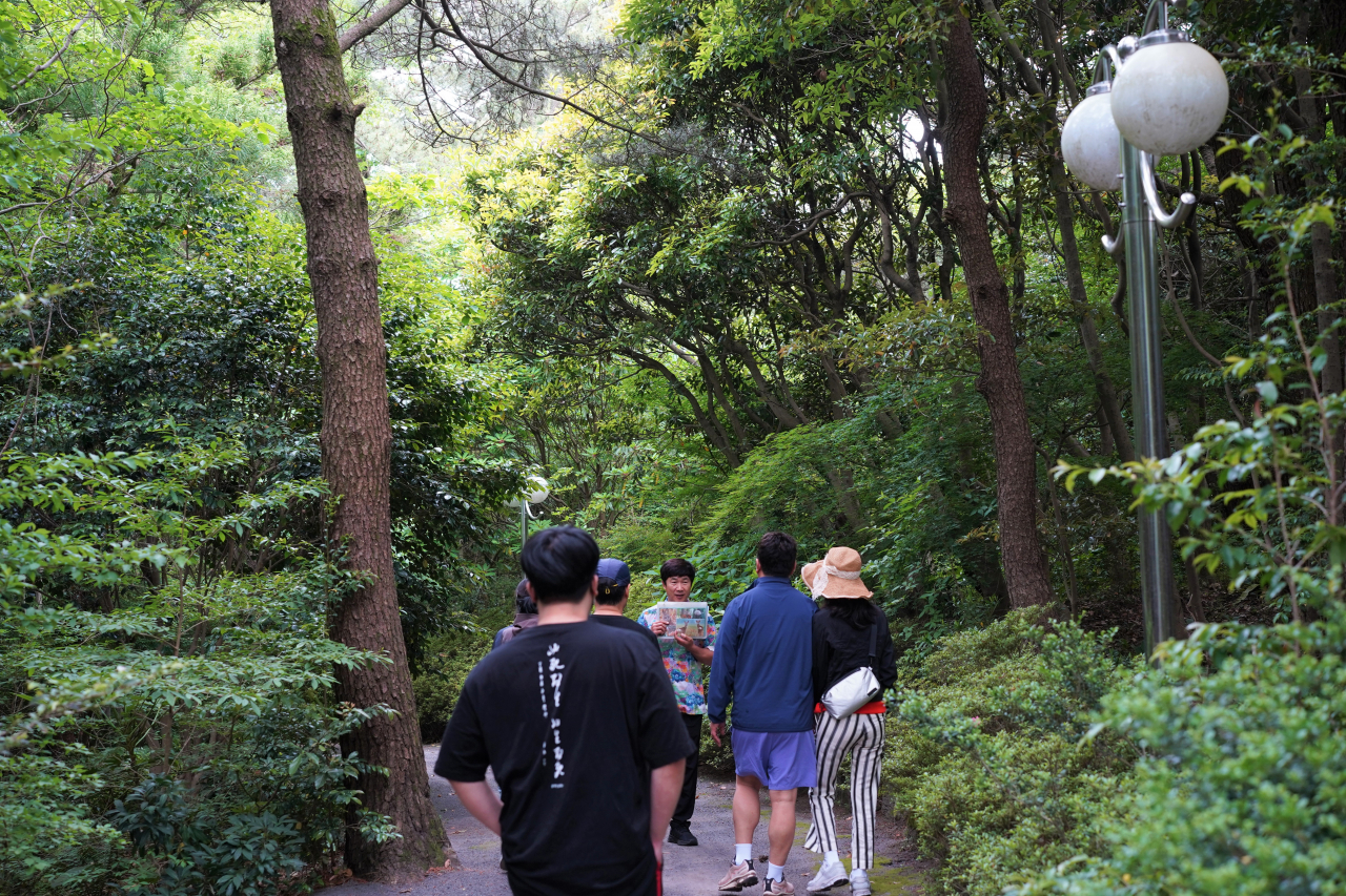 A guide shares Jeju forest-themed stories with visitors to Haeam Forest, next to WE Hotel, on May 22. (Lee Si-jin/The Korea Herald)