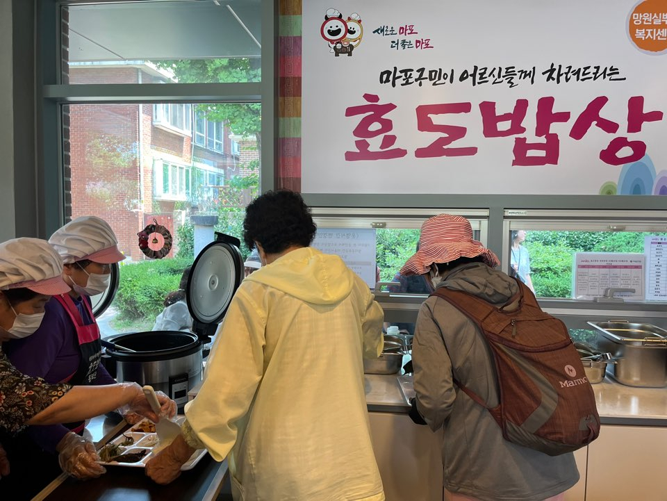 Participants of the Hyodo Babsang initiative take turns putting food on their plates at a senior center in Mangwon-dong, Mapo-gu, Seoul, on May 21. (Lee Jaeeun/The Korea Herald)