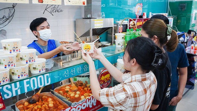 A clerk hands over a cup of tteokbokki to customers at a GS25 store in Vietnam. (GS25)