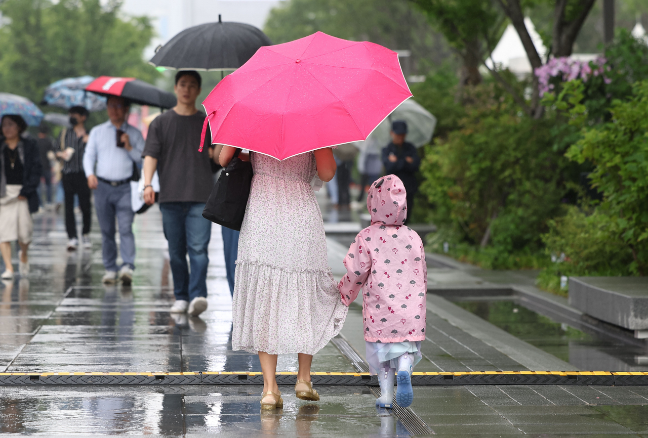 Pedestrians walk through the rain holding umbrellas on May 26. (Yonhap)