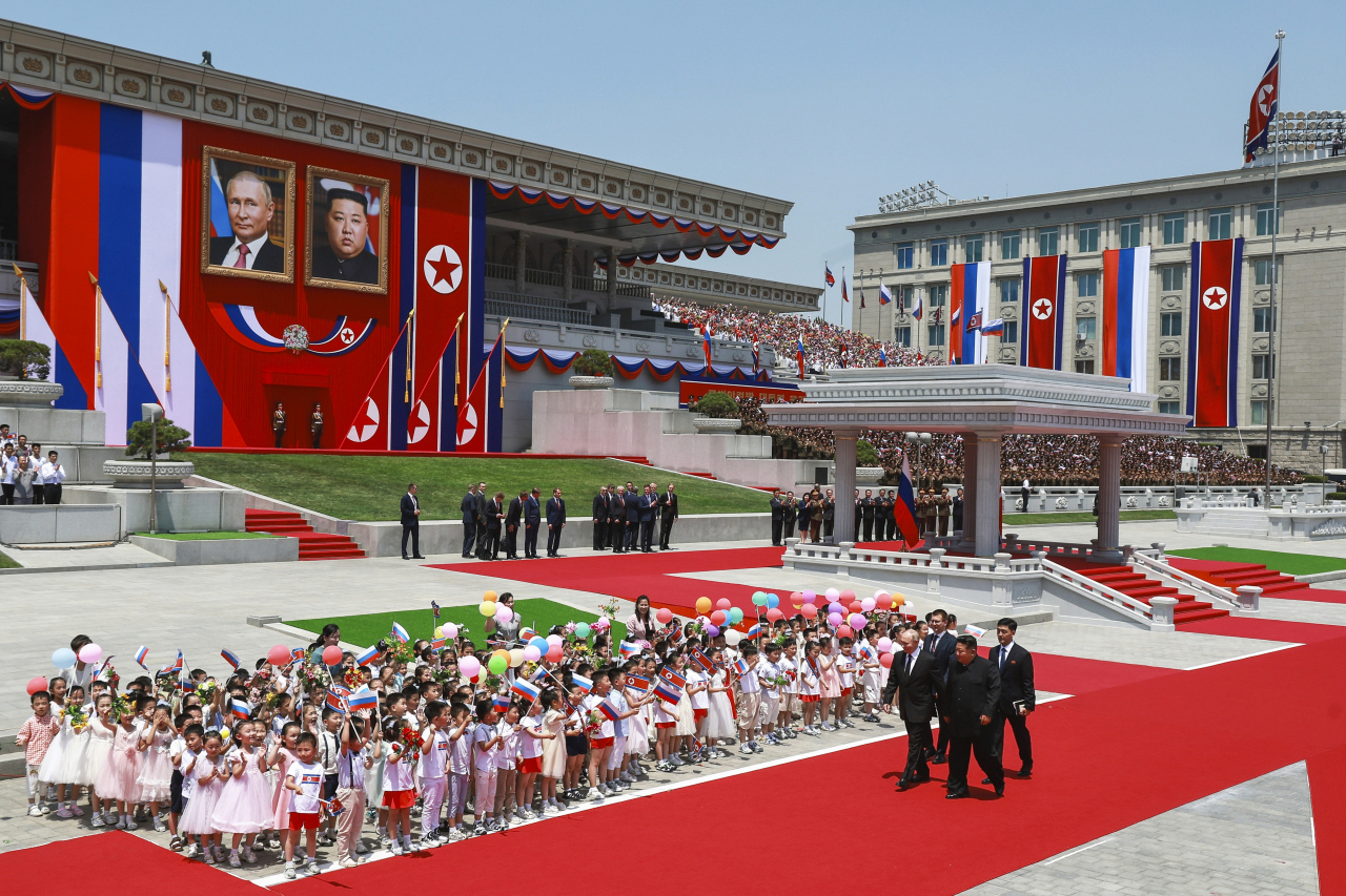 Russian President Vladimir Putin (left) and North Korea's leader Kim Jong Un, foreground (right) attend the official welcome ceremony in the Kim Il Sung Square in Pyongyang, North Korea, on Wednesday, June 19, 2024. (Kremlin Pool Photo via AP)
