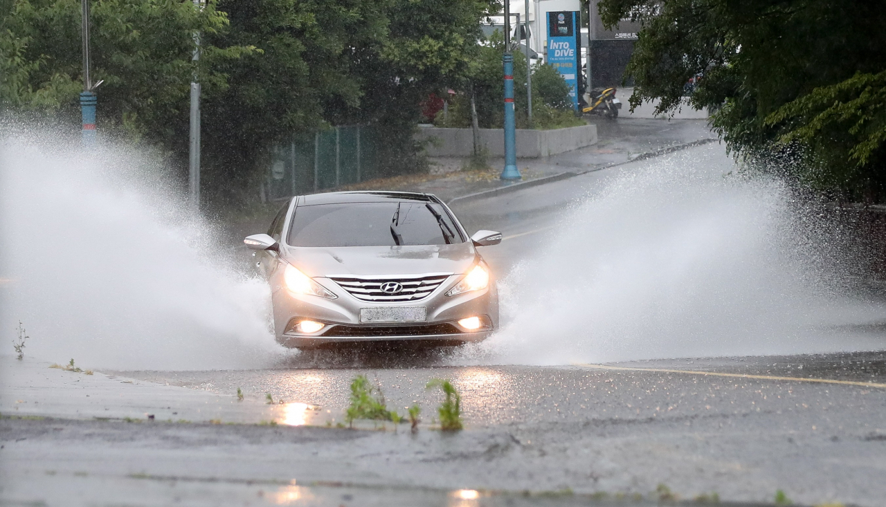A car drives through a large puddle, causing the car to create a big splash at Seogwipo-si, Jeju Island, Thursday. (Newsis)