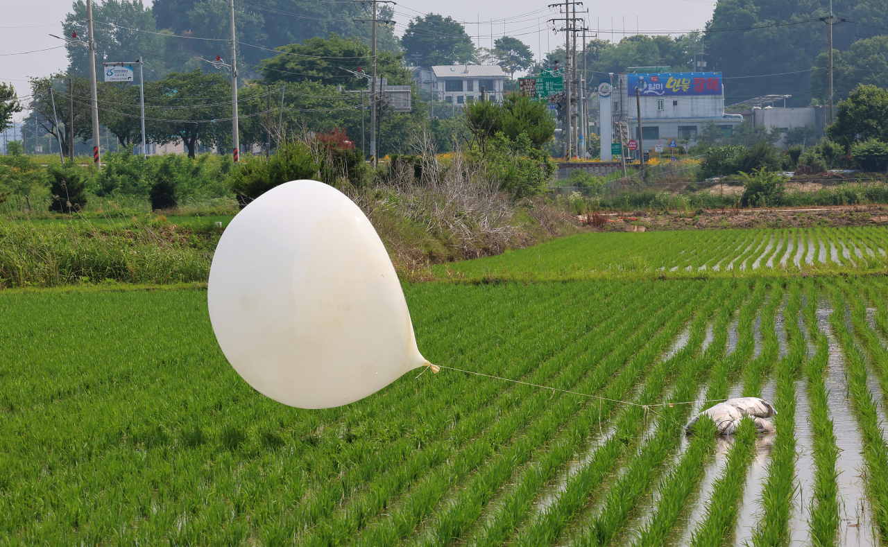 This file photo, taken Jun. 10 shows a balloon carrying trash sent by North Korea in a rice paddy in Incheon, just west of Seoul. (Yonhap)