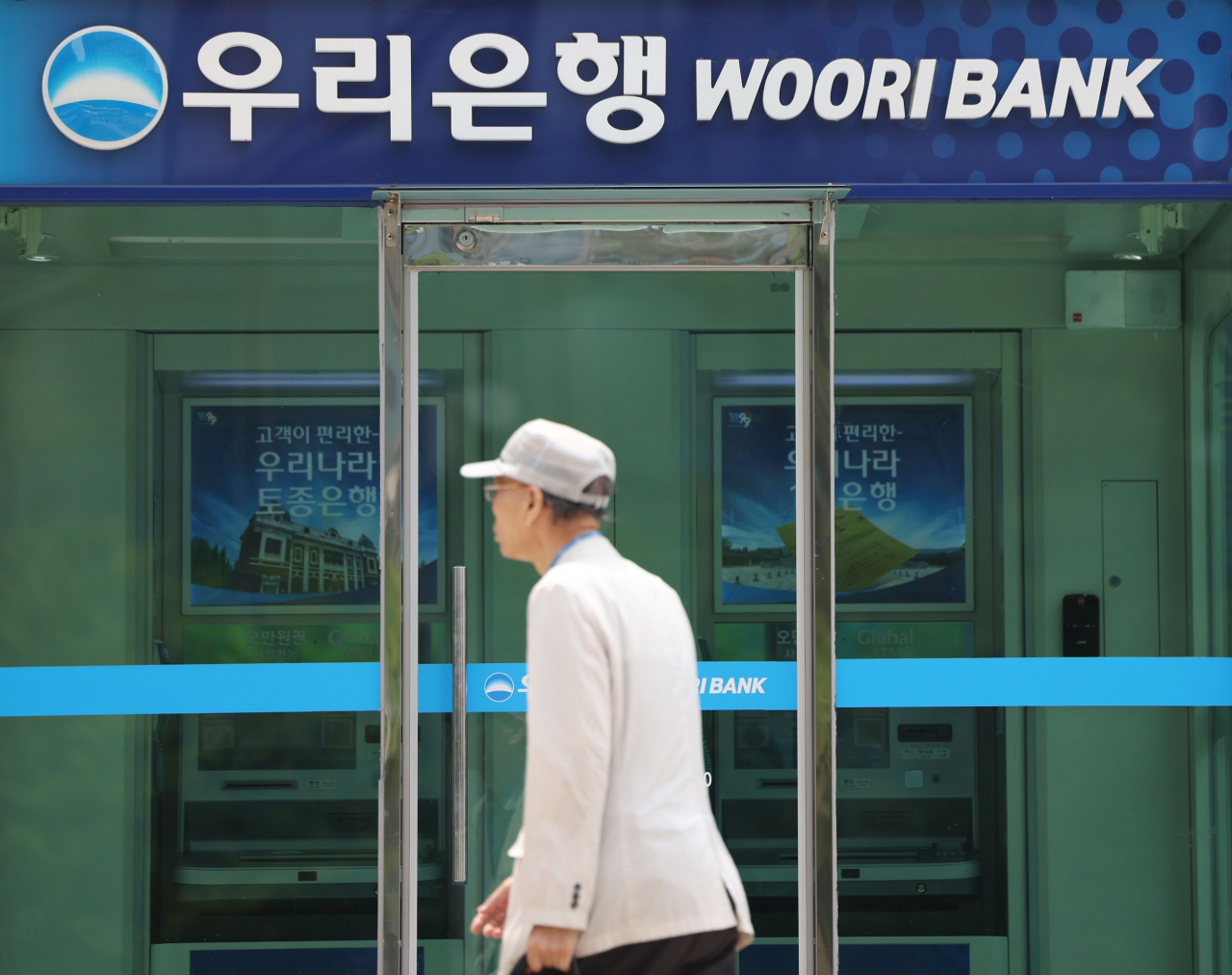 A man walks past an ATM of Woori Bank in Seoul on June 21. (Yonhap)