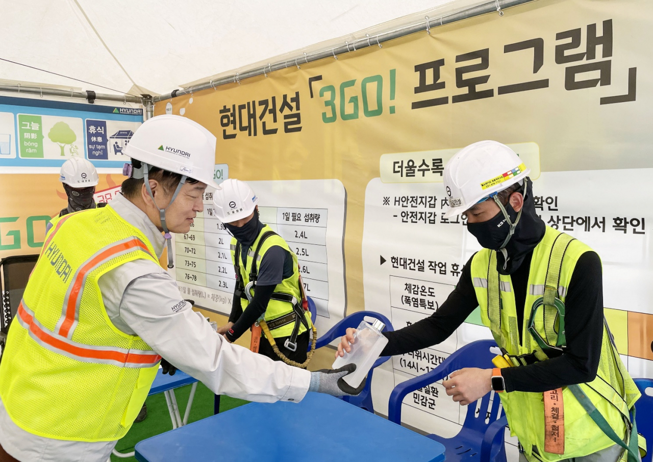 Hwang Joon-ha, CSO of Hyundai E&C, is handing beverages to workers at the company's construction site in Uijeongbu, Gyeonggi Province. (Hyundai E&C)