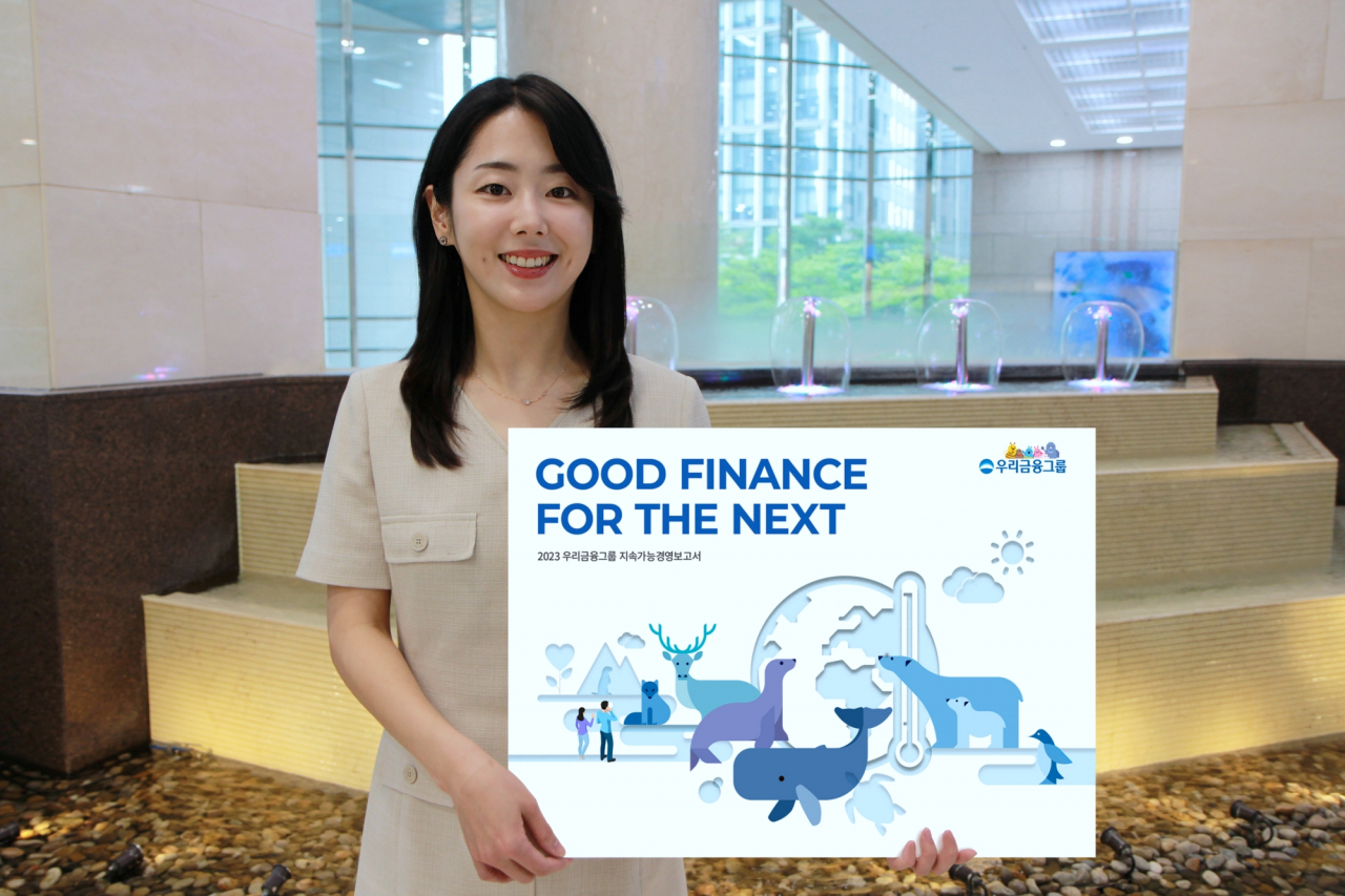An employee of Woori Financial Group poses with a signboard promoting the group's release of the 2023 Sustainability Report. (Woori Financial Group)