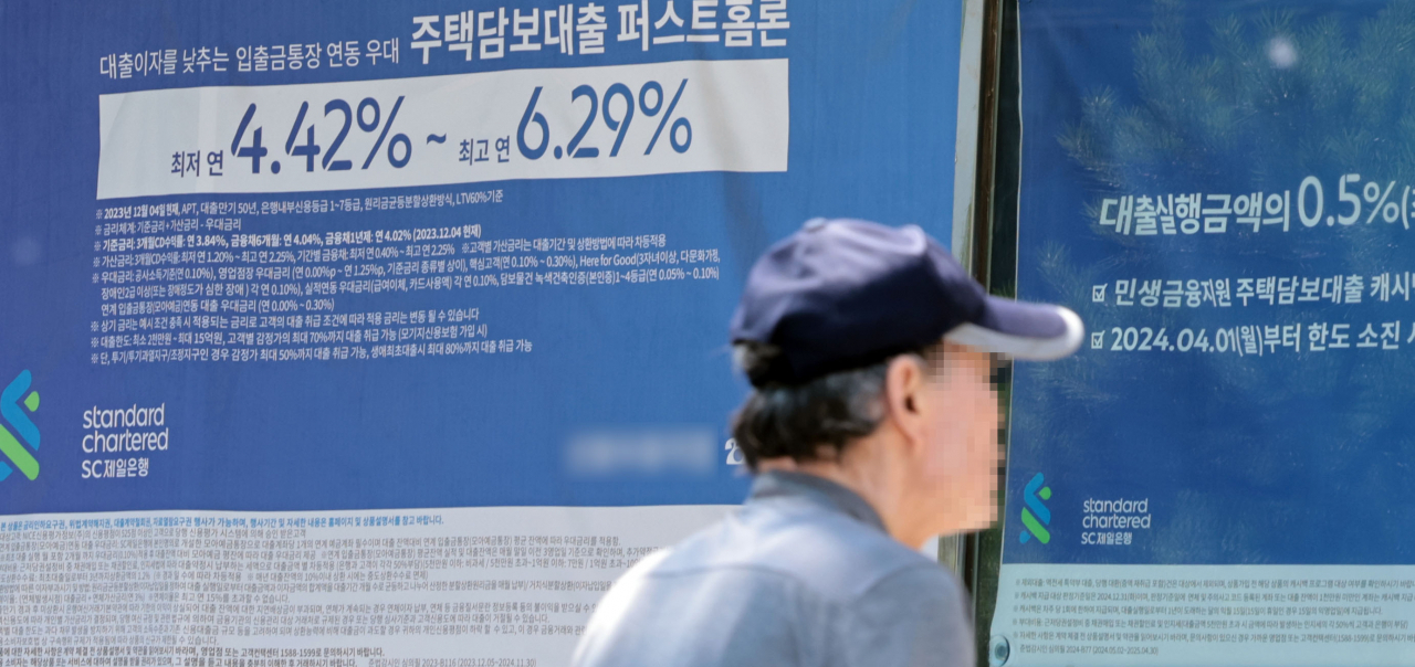 A man walks by a banner promoting a loan product of a Seoul-based bank on June 2. (Yonhap)