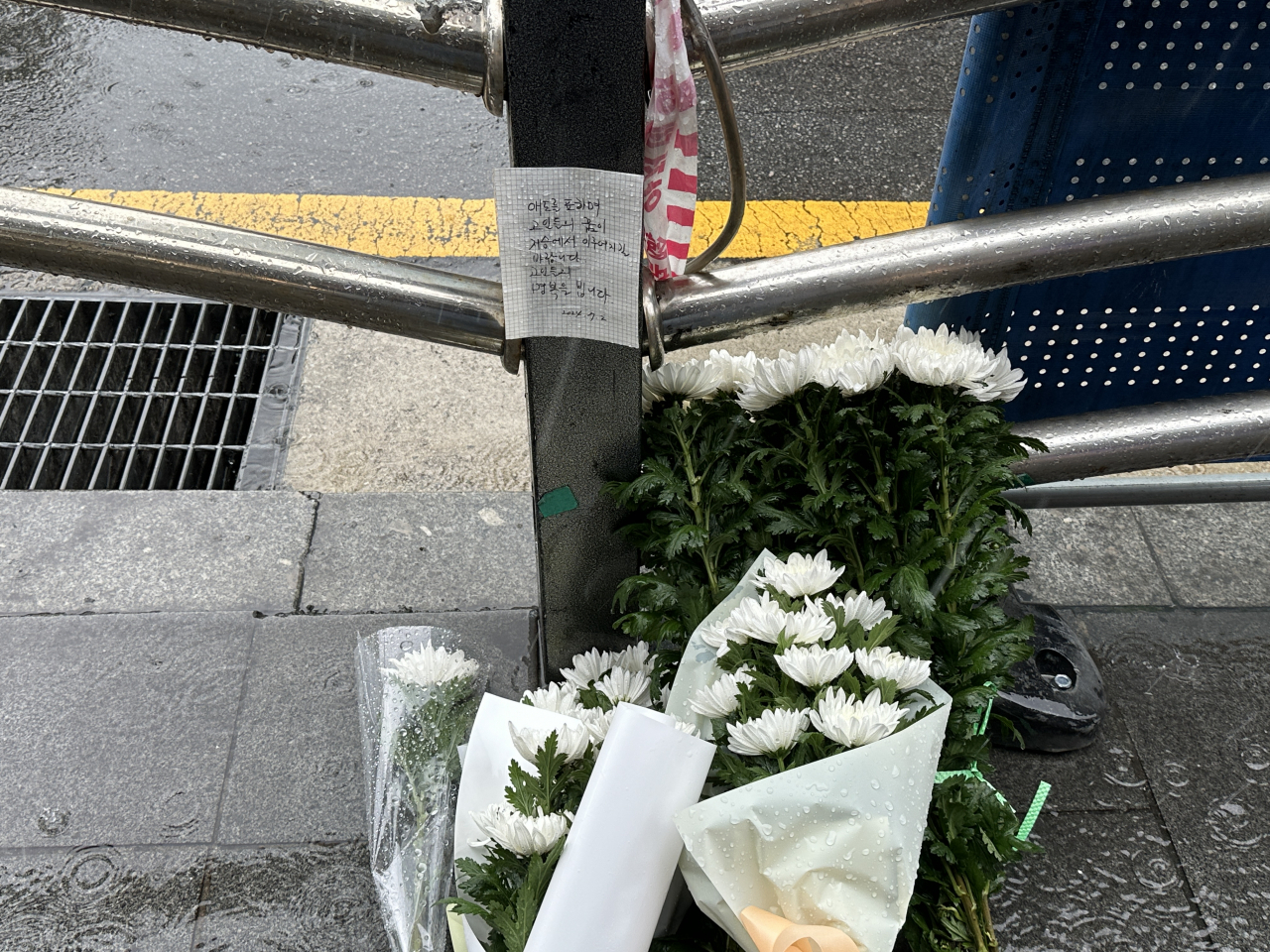 Bouquets of white chrysanthemums with a commemorative note are laid near Exit No. 7 of City Hall Station, Tuesday, the morning after a deadly car crash that resulted in nine casualties. The note reads: “I offer my condolences and hopes for the victims’ dreams to come true in heaven. May they rest in peace.” (Lee Jung-joo/The Korea Herald)