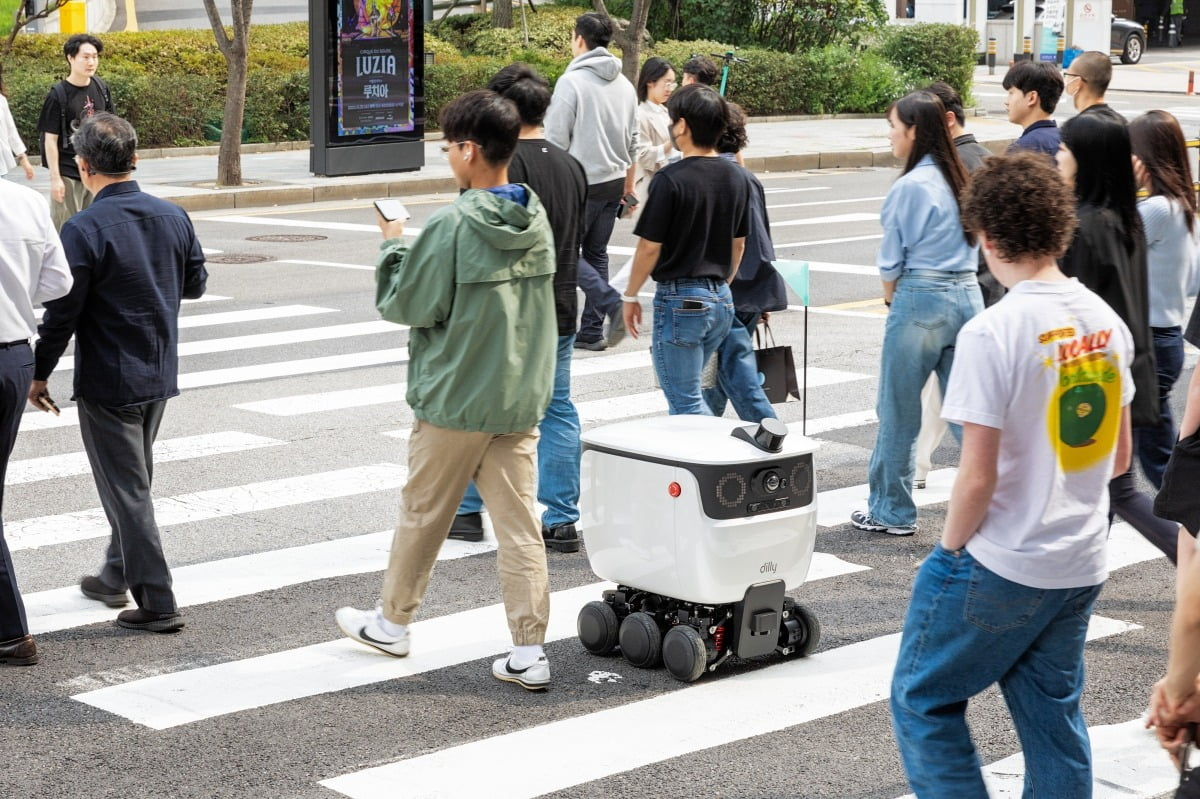 Dilly, a robot that makes food deliveries in and around six designated buildings, crosses the street with pedestrians near Samseong Station in Gangnam-gu, southern Seoul. (Gangnam-gu Office)