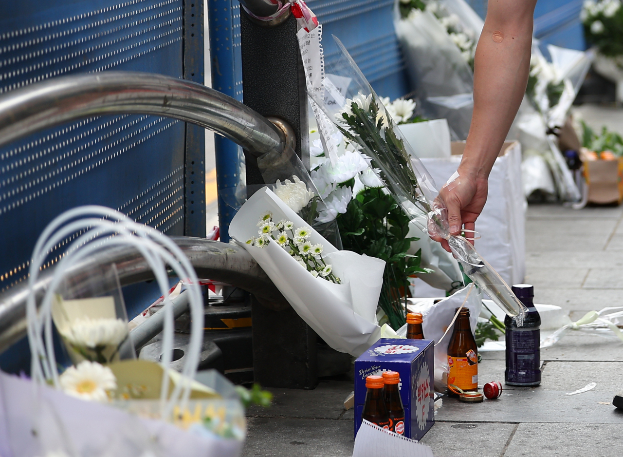 A man lays a flower in front of a guardrail on Wednesday to commemorate those who died during a deadly car crash in central Seoul late Monday. (Yonhap)