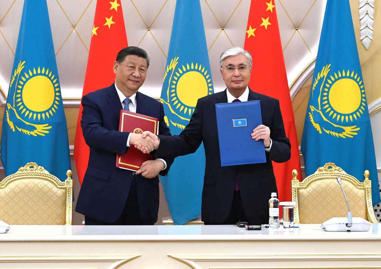 Kazakhstan's President Kassym-Jomart Tokayev (right) and China's President Xi Jinping shake hands during a signing ceremony following their talks in Astana, Kazakhstan, Wednesday, local time. (Reuters-Yonhap)