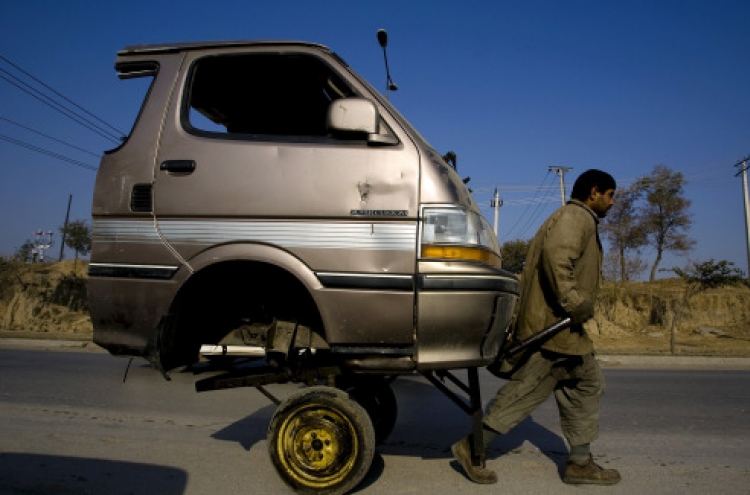 A Pakistani laborer transporting the front portion of a van