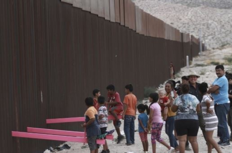 회색빛 미국-멕시코 국경에 설치된 화합의 분홍 시소