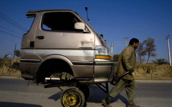 A Pakistani laborer transporting the front portion of a van