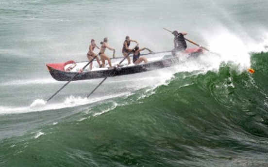 Women's surf boat hit by big wave