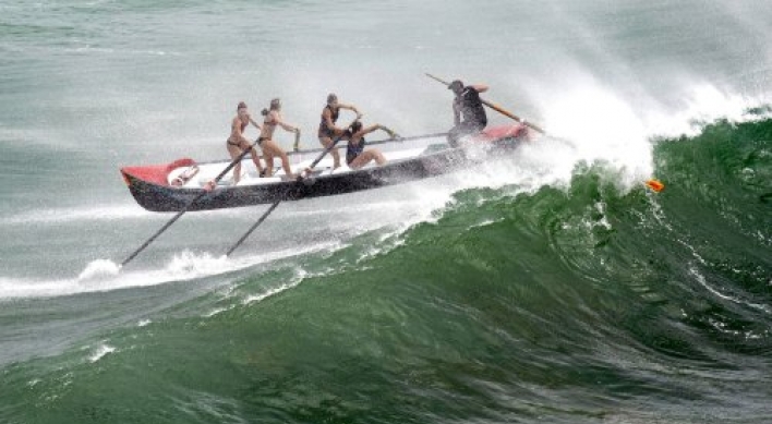 Women's surf boat hit by big wave