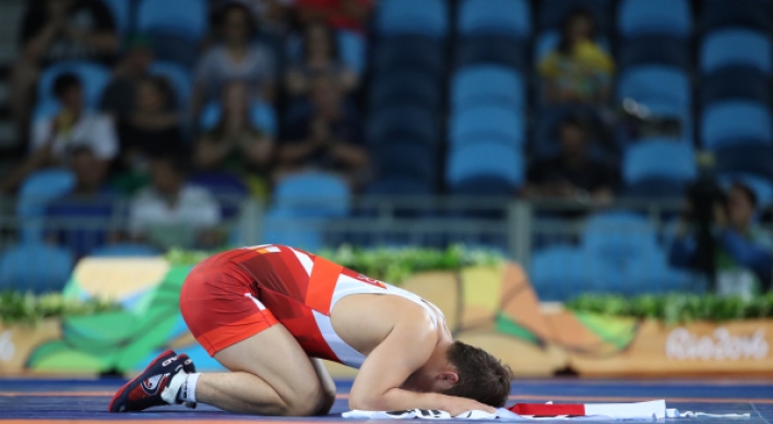 Ex-gold medalist bows out of first round in wrestling